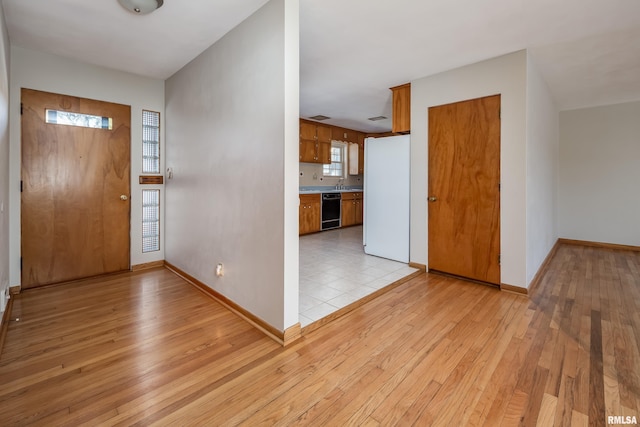 foyer entrance featuring light wood-style flooring and baseboards