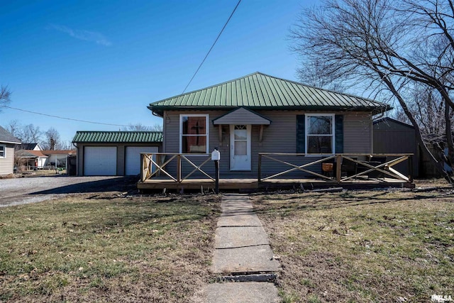 bungalow-style home featuring metal roof, an outdoor structure, driveway, and a front lawn