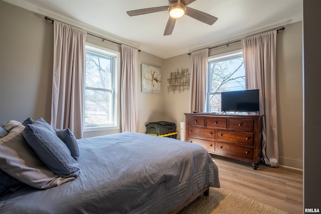 bedroom with crown molding, ceiling fan, light wood-type flooring, and baseboards