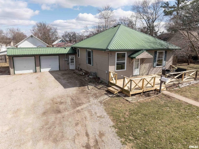 view of front of home with dirt driveway, metal roof, an attached garage, and a wooden deck