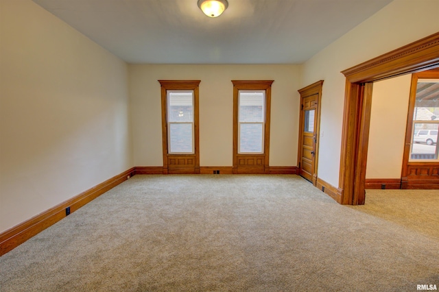 empty room with baseboards, a wealth of natural light, and light colored carpet