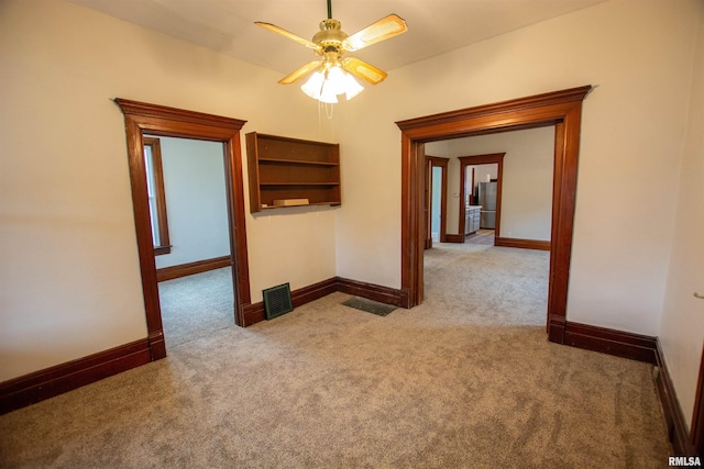 unfurnished room with baseboards, ceiling fan, visible vents, and light colored carpet