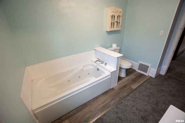 full bath featuring toilet, wood finished floors, visible vents, baseboards, and a whirlpool tub