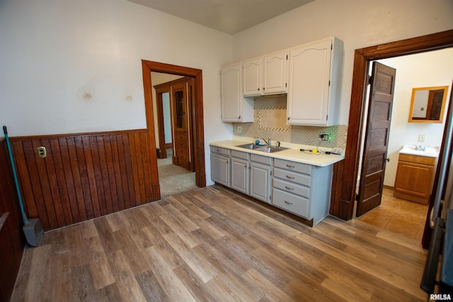 kitchen with light wood-type flooring, white cabinetry, light countertops, and wainscoting