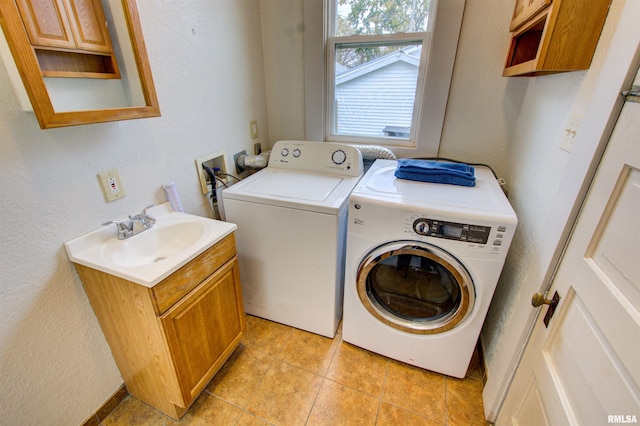 washroom with cabinet space, washer and clothes dryer, a sink, and a textured wall