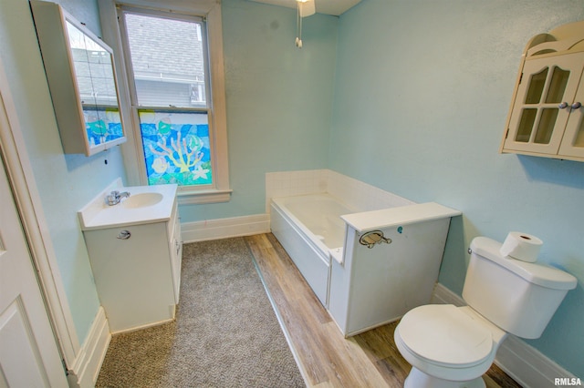 full bath with baseboards, toilet, wood finished floors, vanity, and a bath