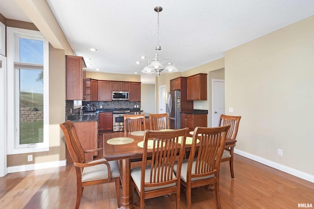 dining space featuring hardwood / wood-style flooring, baseboards, a textured ceiling, and recessed lighting