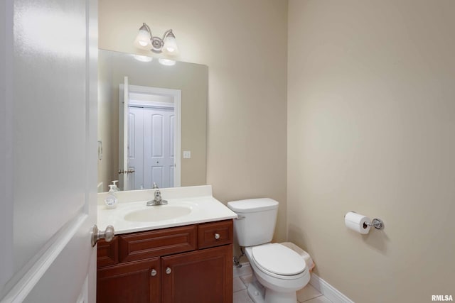 half bathroom with toilet, baseboards, vanity, and tile patterned floors