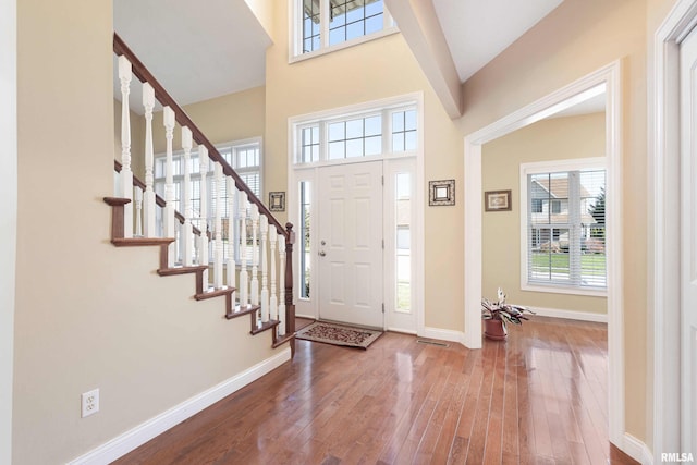 foyer with baseboards, a towering ceiling, hardwood / wood-style floors, and stairs