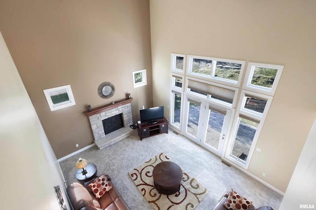 living area with light colored carpet, a fireplace, visible vents, baseboards, and a towering ceiling