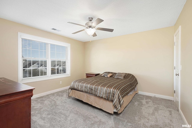 bedroom featuring light colored carpet, visible vents, baseboards, and a textured ceiling