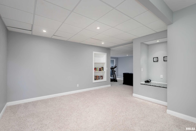 interior space featuring built in shelves, recessed lighting, a paneled ceiling, light carpet, and baseboards