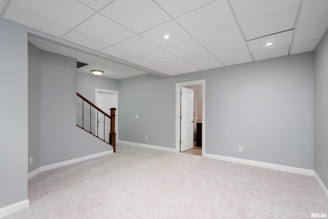 spare room featuring a drop ceiling, recessed lighting, light colored carpet, baseboards, and stairs