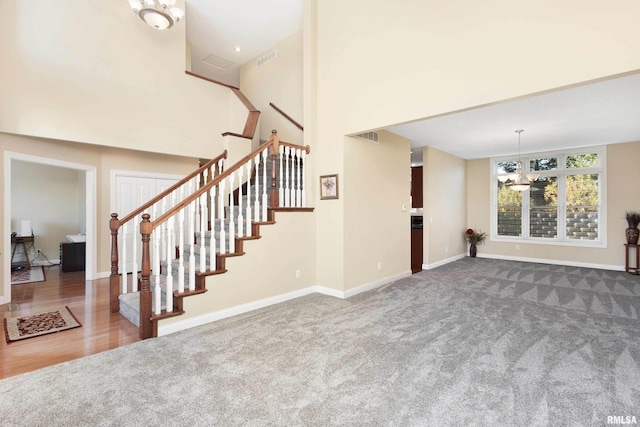 interior space featuring visible vents, baseboards, stairs, dark carpet, and an inviting chandelier