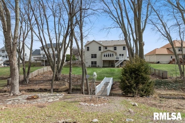 back of house featuring a yard, fence, and stairs