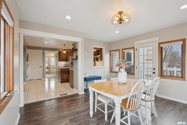 dining room with light wood-type flooring, a healthy amount of sunlight, and baseboards