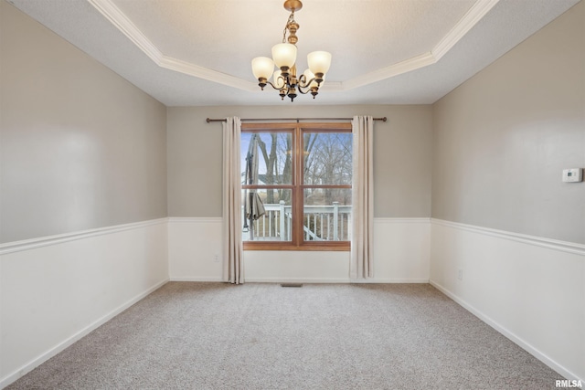 carpeted empty room with a notable chandelier, visible vents, baseboards, a tray ceiling, and crown molding