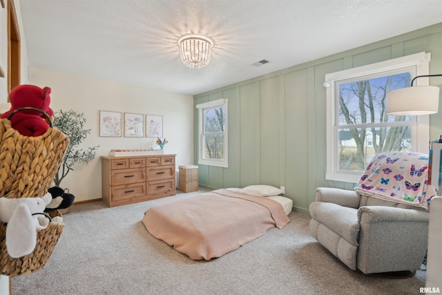 bedroom featuring multiple windows, visible vents, a decorative wall, and light colored carpet