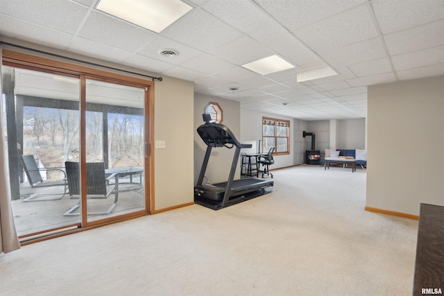 workout area with a wood stove, visible vents, carpet floors, and baseboards