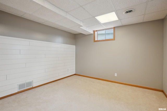 below grade area with baseboards, visible vents, a drop ceiling, and carpet flooring