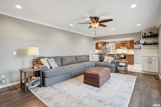 living room with ornamental molding, ceiling fan, baseboards, and wood finished floors