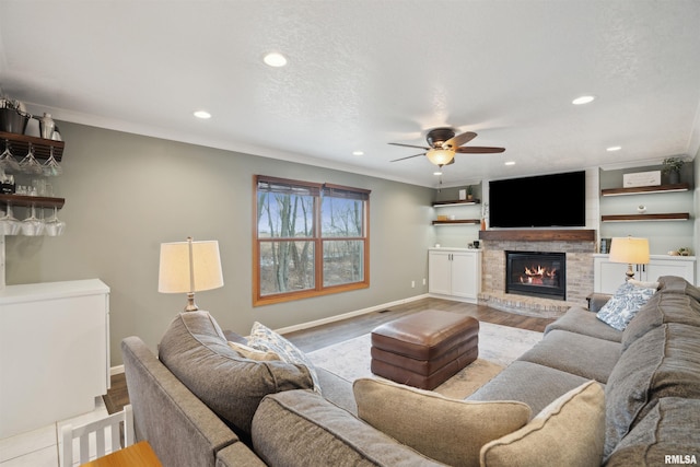 living area with light wood-style flooring, a fireplace, ornamental molding, and a textured ceiling