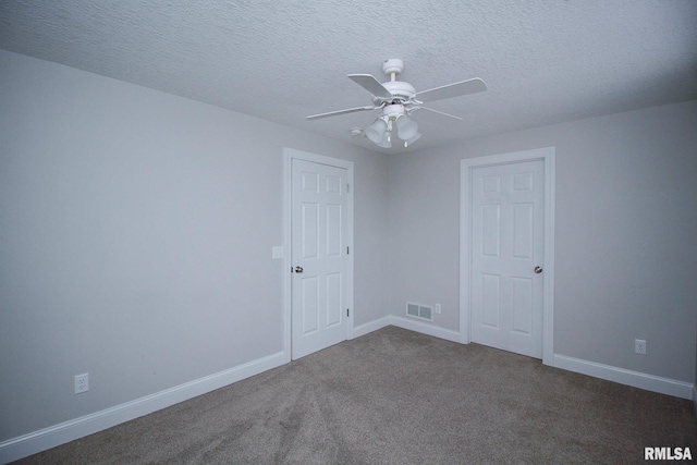 spare room with visible vents, dark carpet, a ceiling fan, a textured ceiling, and baseboards