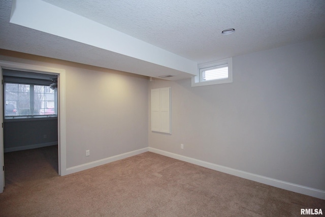 basement with light carpet, a textured ceiling, and baseboards