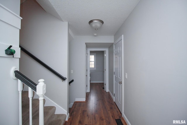 corridor featuring baseboards, visible vents, a textured ceiling, and wood finished floors