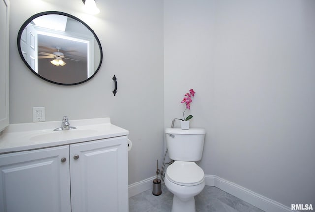 half bathroom with baseboards, vanity, and toilet