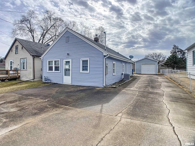 view of front of house with an outbuilding, a garage, fence, concrete driveway, and a chimney