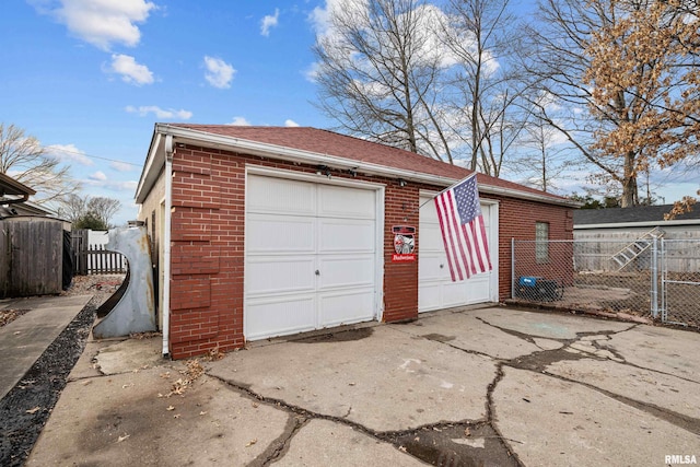 detached garage featuring concrete driveway, fence, and a gate