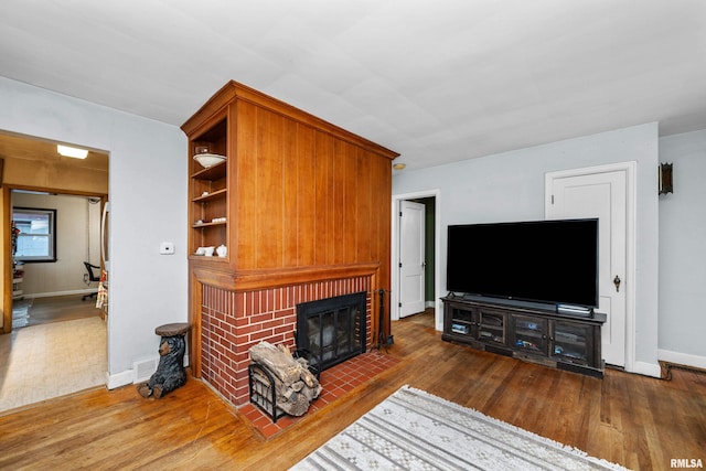 living area featuring hardwood / wood-style floors, a fireplace, visible vents, and baseboards