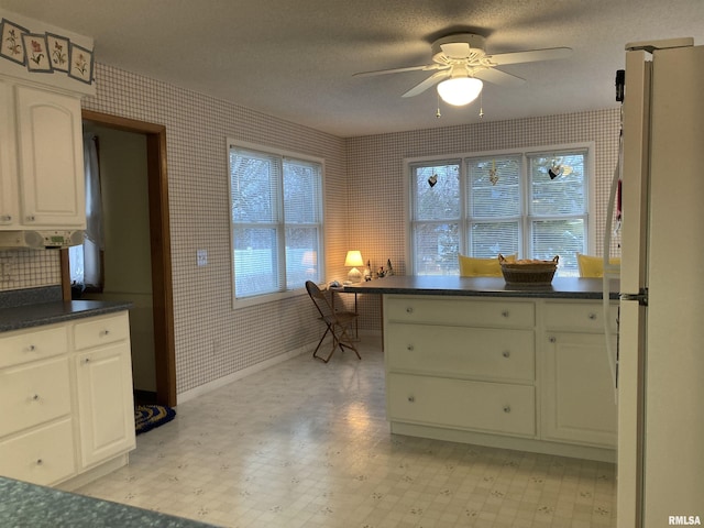 kitchen with wallpapered walls, dark countertops, light floors, and freestanding refrigerator