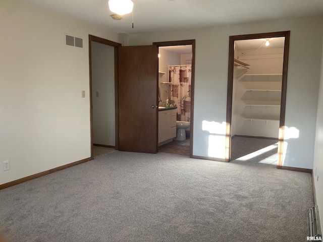 unfurnished bedroom featuring visible vents, baseboards, a walk in closet, and carpet flooring