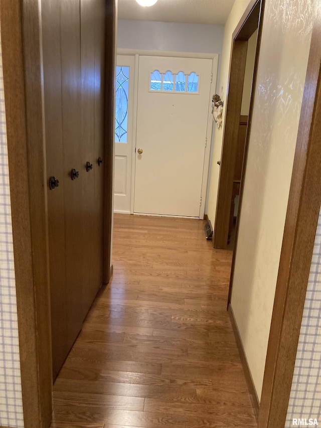 hall with light wood-type flooring and baseboards