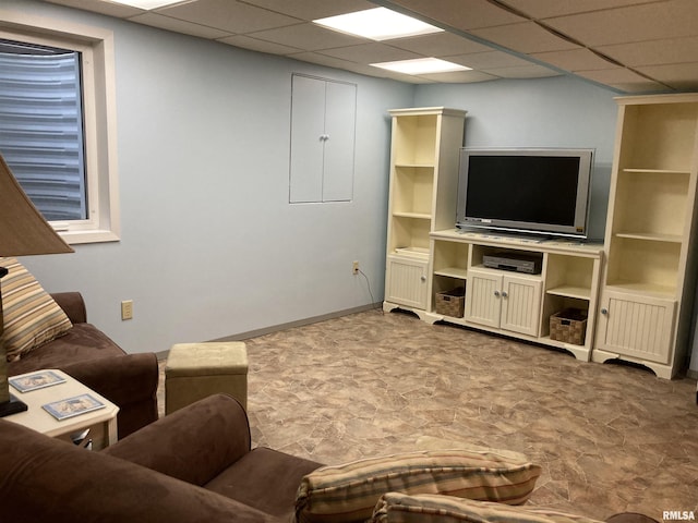 living area with a drop ceiling and baseboards