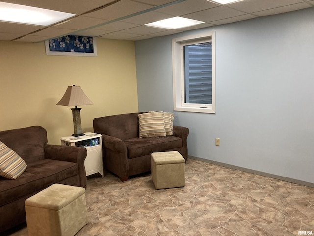 living area featuring baseboards and a paneled ceiling