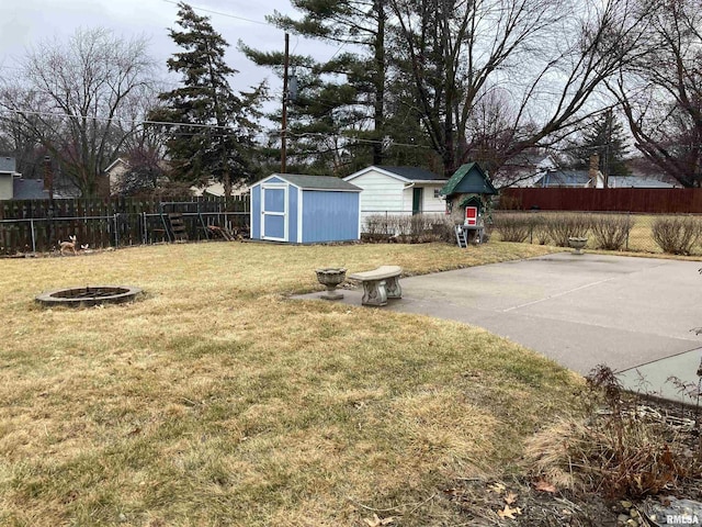 view of yard with an outdoor fire pit, a storage shed, a fenced backyard, and an outdoor structure