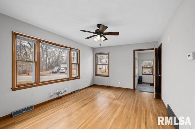 unfurnished room with ceiling fan, light wood-type flooring, visible vents, and baseboards