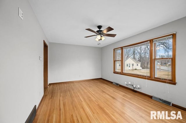 spare room with ceiling fan, light wood-style flooring, visible vents, and baseboards