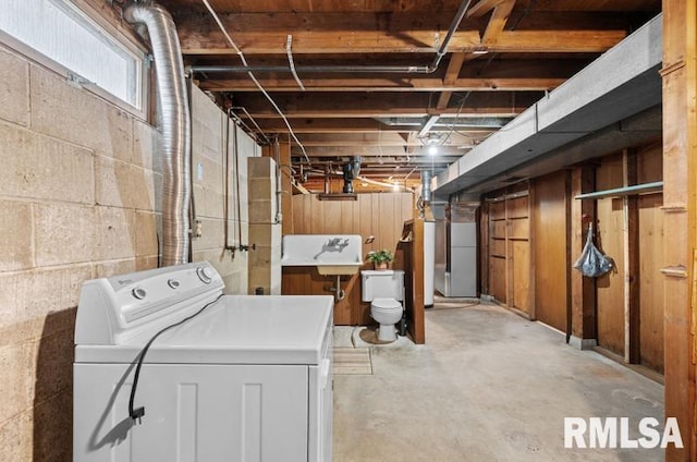 below grade area with washer / clothes dryer, water heater, and a sink