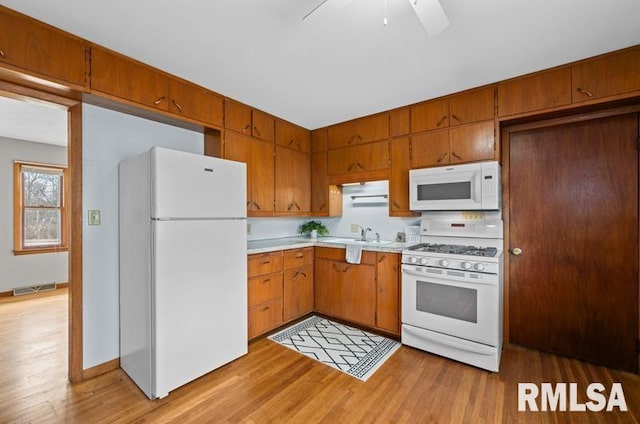 kitchen with white appliances, visible vents, light countertops, brown cabinets, and light wood finished floors