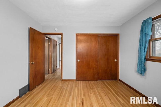 unfurnished bedroom with a closet, visible vents, light wood-style flooring, and baseboards