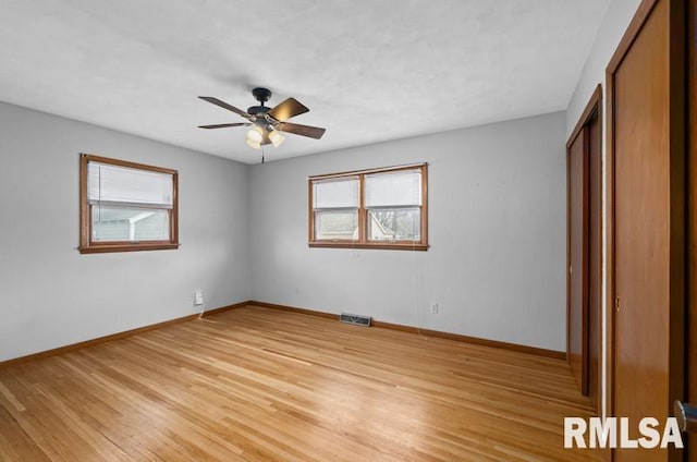 unfurnished bedroom with light wood finished floors, baseboards, visible vents, a ceiling fan, and a closet