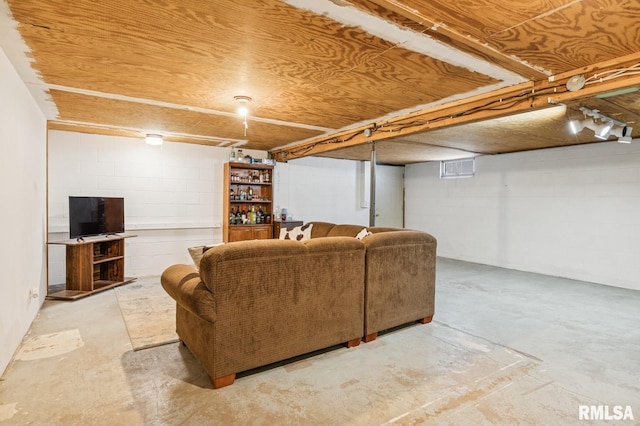 living room with concrete block wall and unfinished concrete flooring