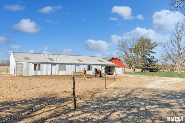 view of front of home with a garage, an outbuilding, metal roof, and dirt driveway