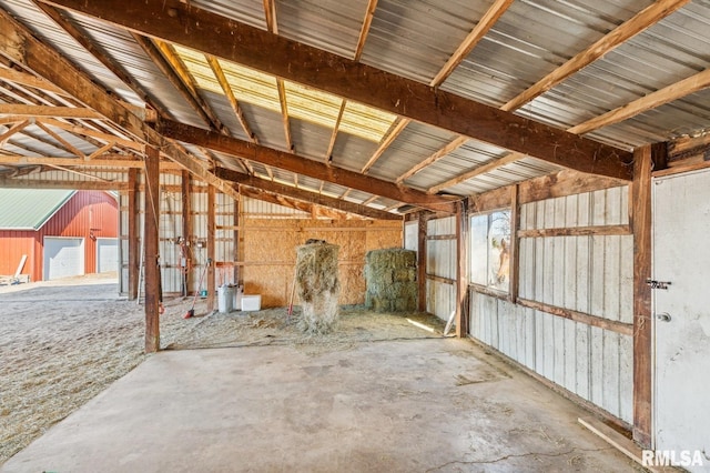 misc room featuring concrete flooring, lofted ceiling, and metal wall