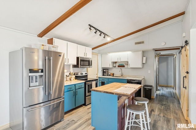 kitchen featuring lofted ceiling, blue cabinets, stainless steel appliances, a sink, and white cabinetry