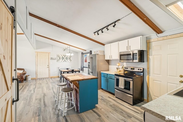 kitchen with lofted ceiling with beams, stainless steel appliances, a breakfast bar, wood counters, and white cabinetry